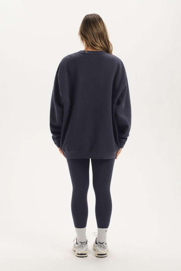 Person wearing a navy oversized sweatshirt and leggings on a white background