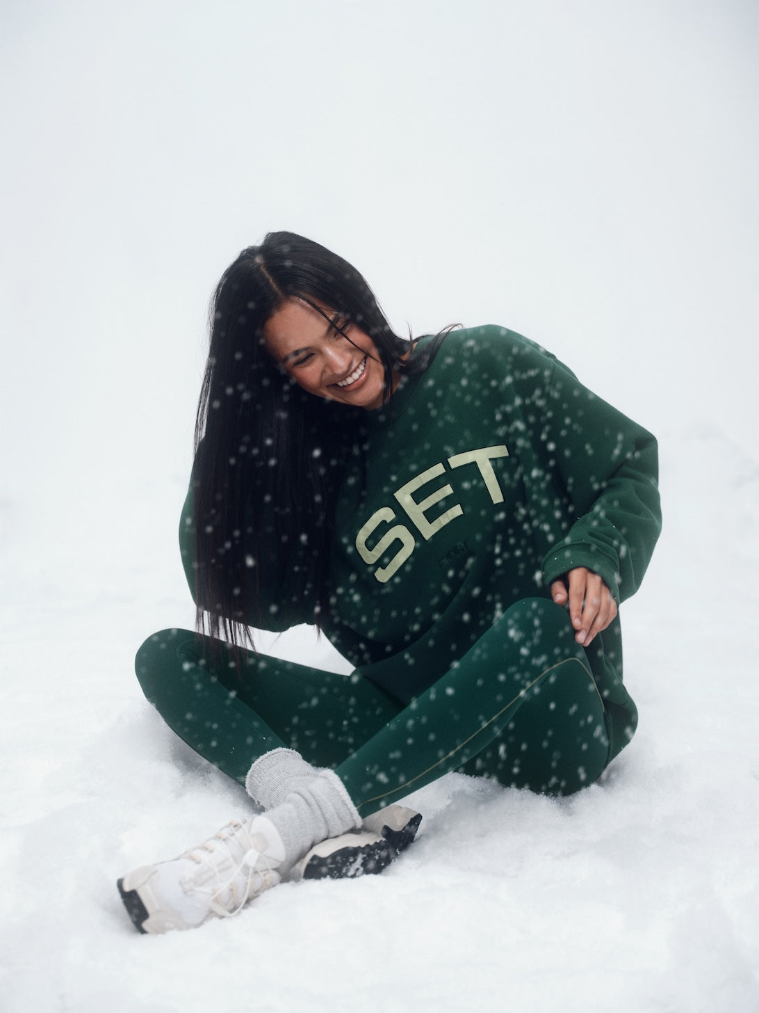 Person wearing a green 'SET' sweater sitting in the snow