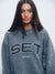 Woman wearing a gray sweatshirt with 'SET Sport' branding on a light gray background