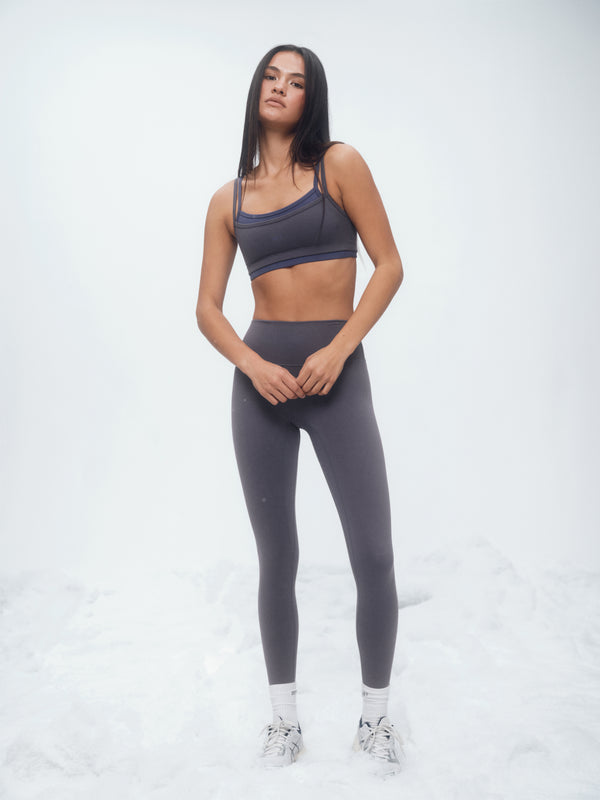 Woman wearing a gray athletic outfit on a white background