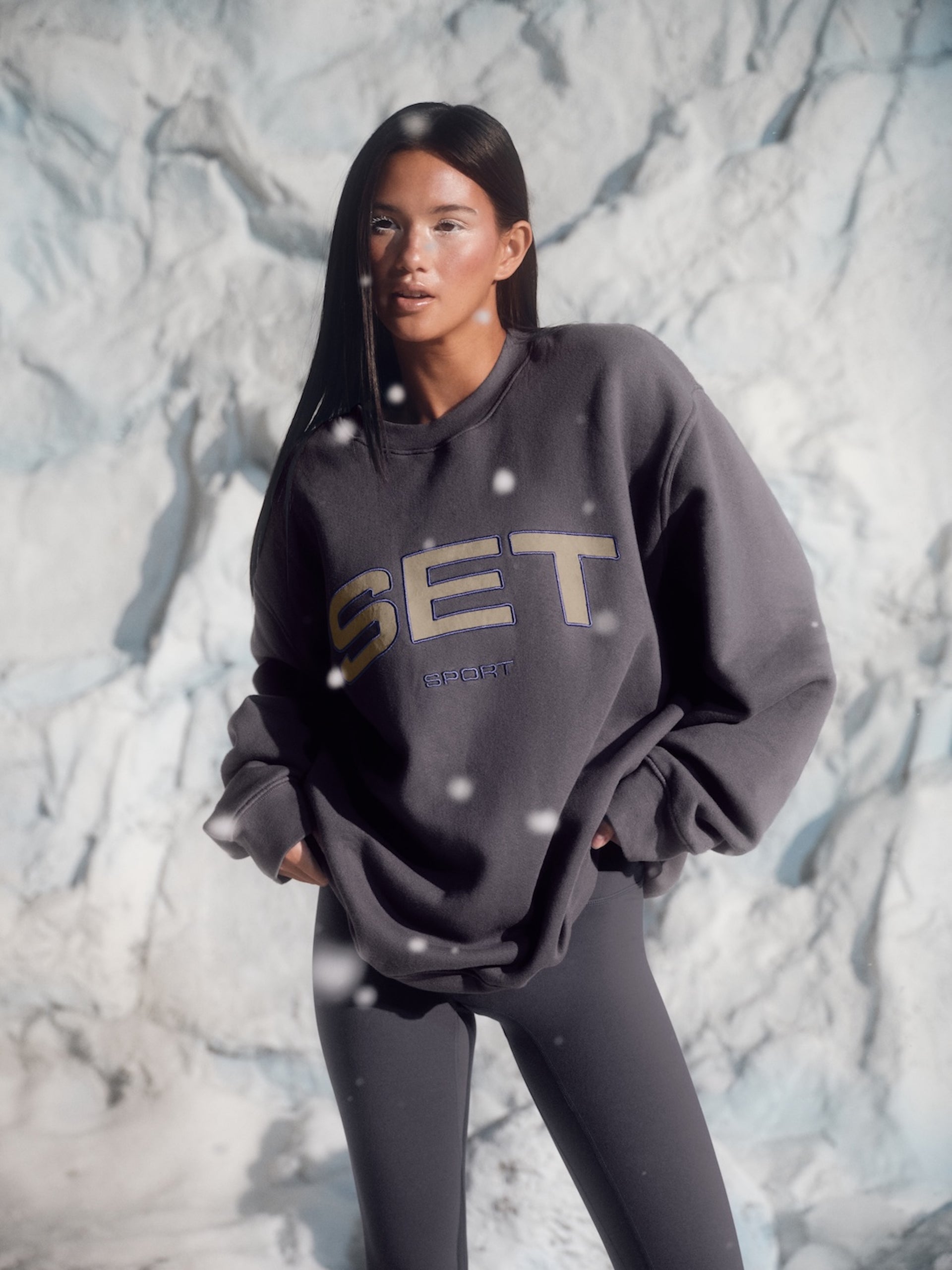 Person wearing a dark gray sweatshirt with 'SET' logo against a snowy background