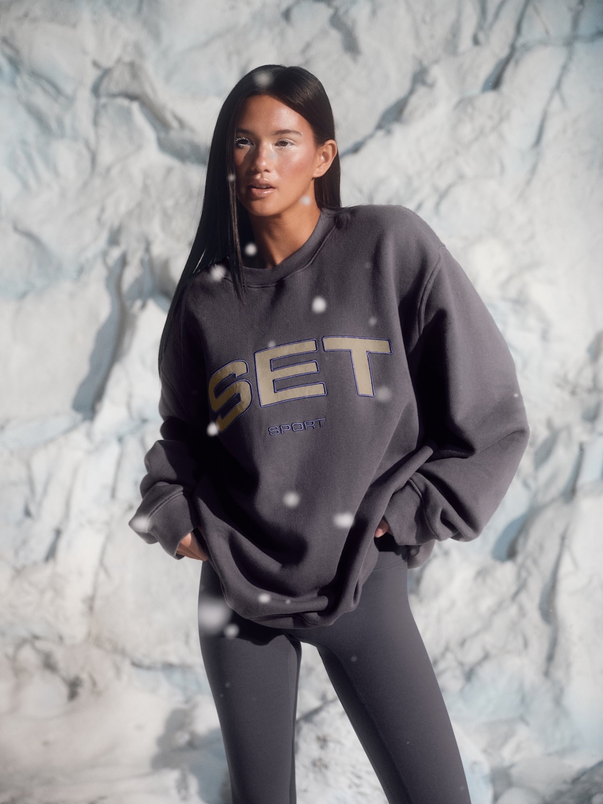 Person wearing a dark gray sweatshirt with 'SET' logo against a snowy background