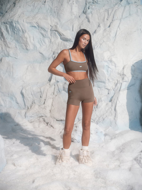 Woman in athletic wear standing against a snowy mountain background