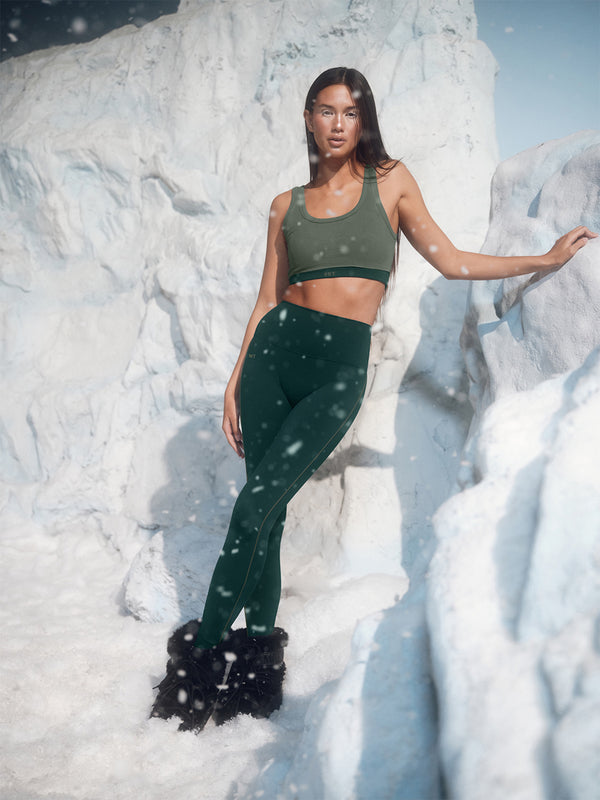 Person wearing green athletic wear standing in a snowy landscape