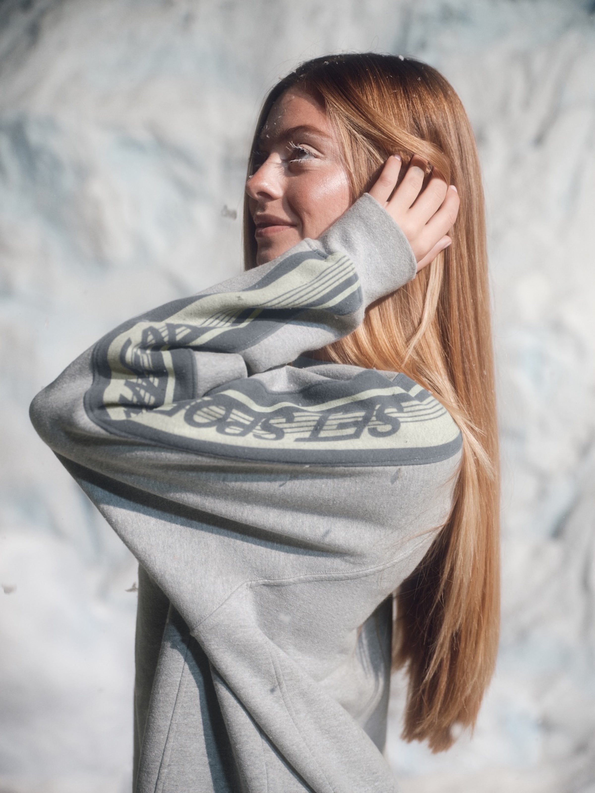 Woman wearing a gray hoodie with a brand logo against a snowy background