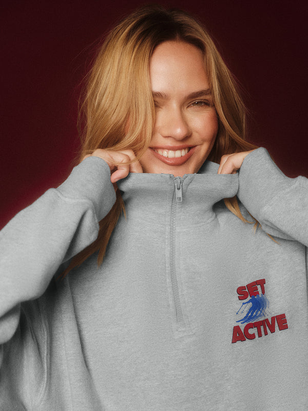 Woman wearing a gray hoodie with 'Set Active' logo on a dark red background