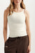 Woman wearing a white tank top and brown pants on a white background