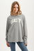 Woman wearing a gray long sleeve with 'SET' text on a white background <model-info>Maranda wears a size XS and is 5’10”, 24½” waist, 33” bust.</model-info>