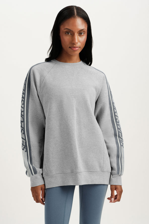 Woman wearing a gray sweatshirt with striped sleeves on a white background 