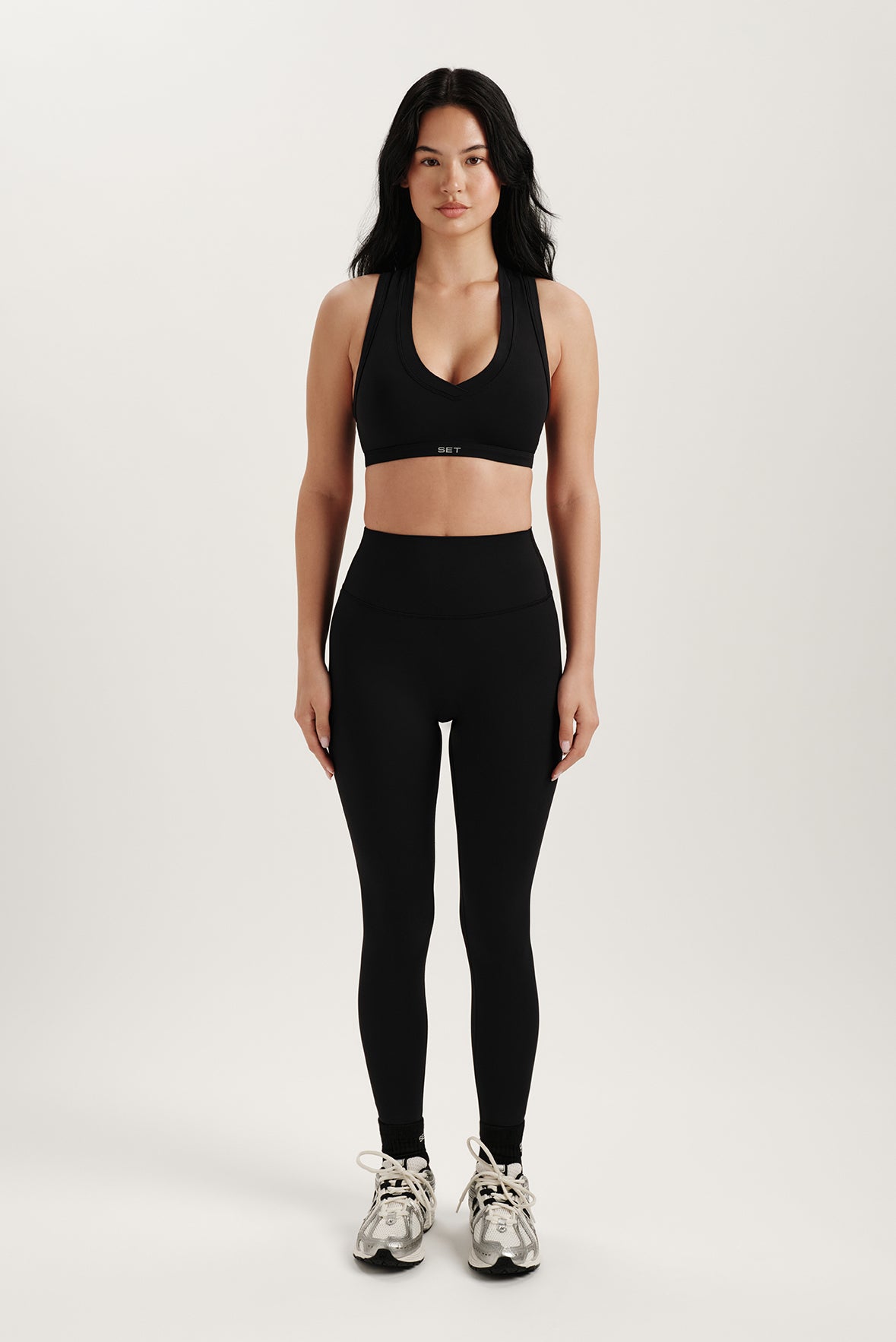 Woman wearing a black sports bra and leggings on a white background
