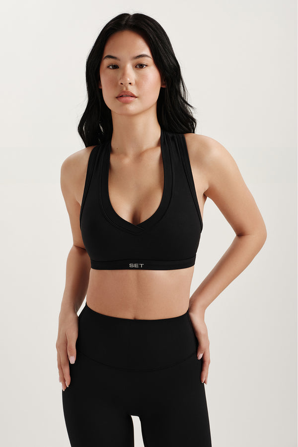 Woman wearing a black sports bra and leggings on a light background 