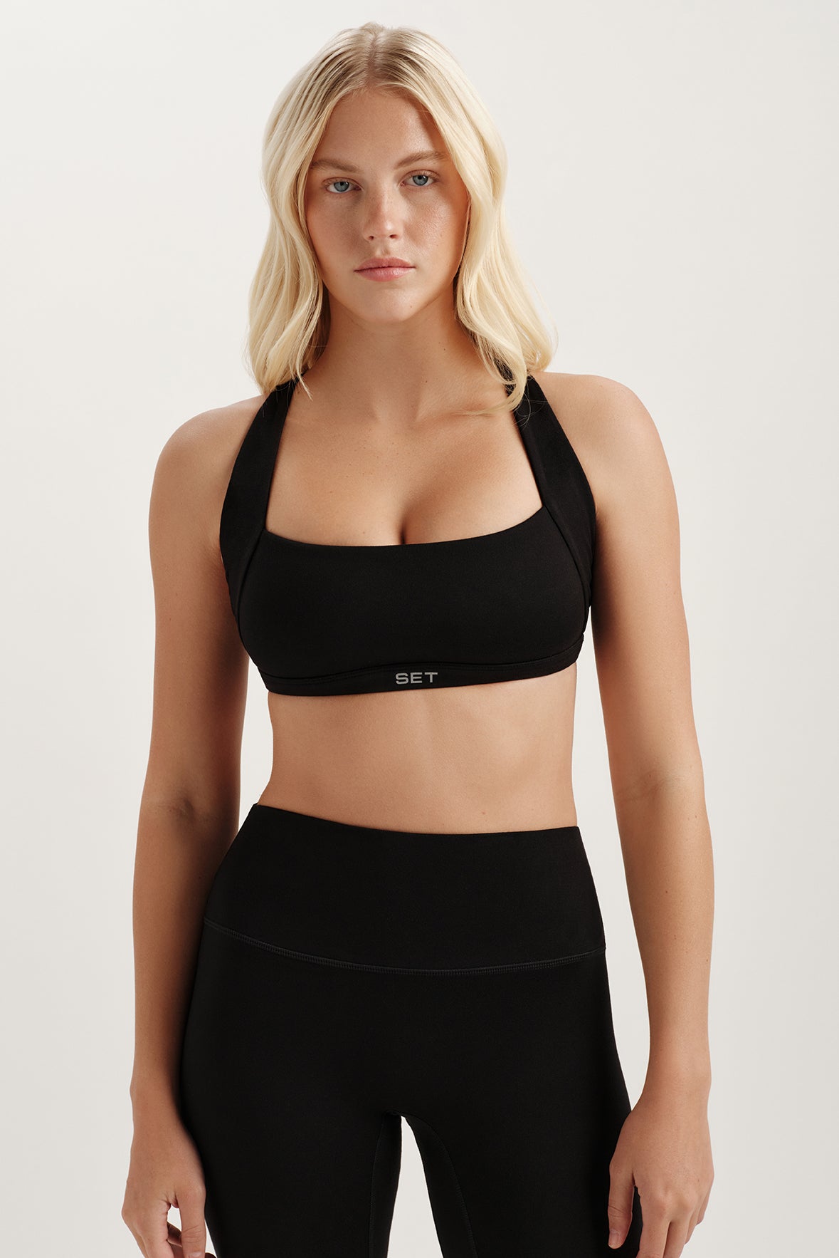 Woman wearing a black sports bra and leggings on a white background 
