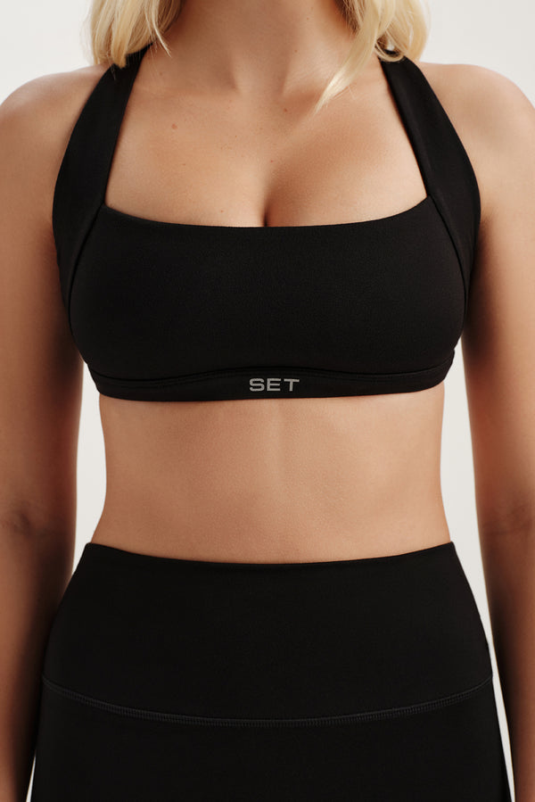 Black sports bra with 'SET' logo on a neutral background