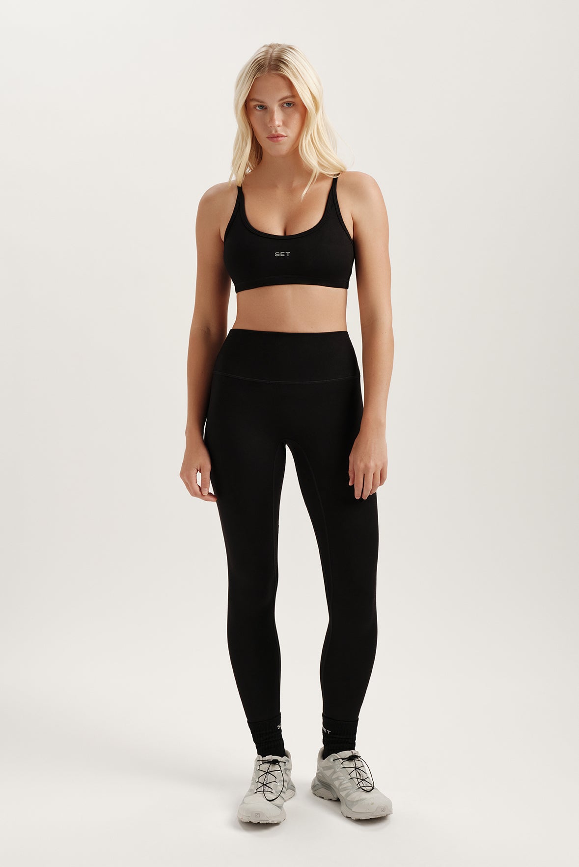 Woman wearing a black sports bra and leggings on a white background