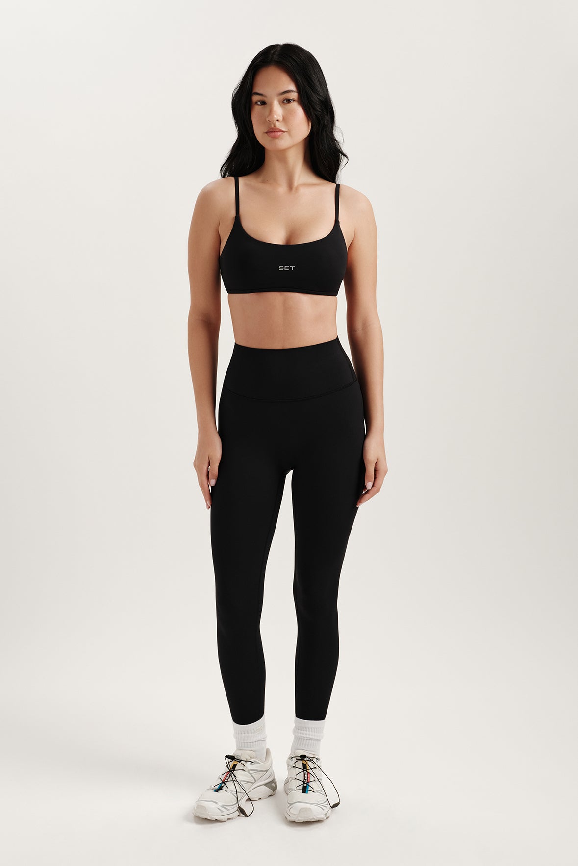 Woman wearing a black sports bra and leggings on a white background