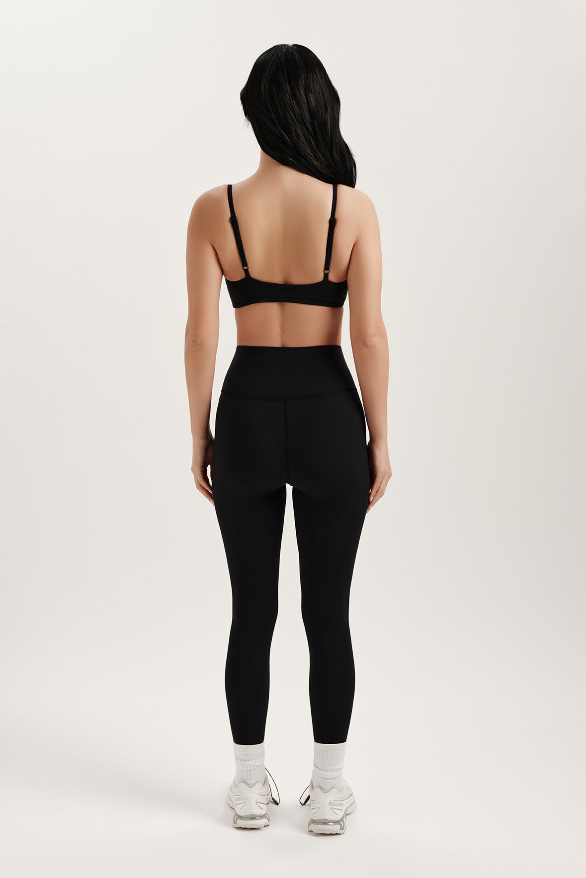 Person wearing a black sports bra and leggings set on a white background