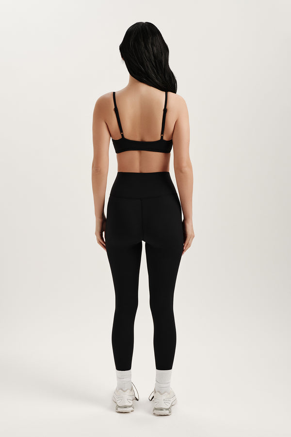 Person wearing a black sports bra and leggings set on a white background