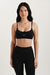 Woman wearing a black sports bra and leggings with 'SET' branding on a light background <model-info>Jasmine wears a size S and is 5’8, 25” waist, 32C bust.</model-info> 