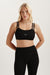 Woman wearing a black sports bra and leggings with a visible brand logo on a light background <model-info>Kenzie wears a size S and is 5’6, 25” waist, 33” bust.</model-info>