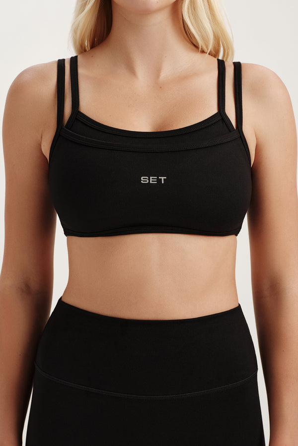 Black sports bra with 'SET' branding worn by a person on a light background