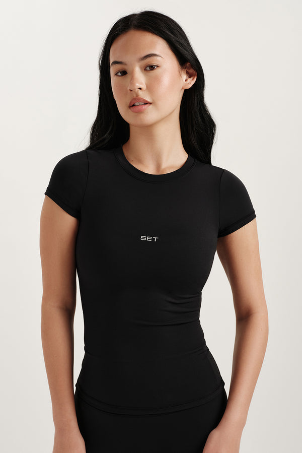 Woman wearing a black t-shirt with a logo on a white background 