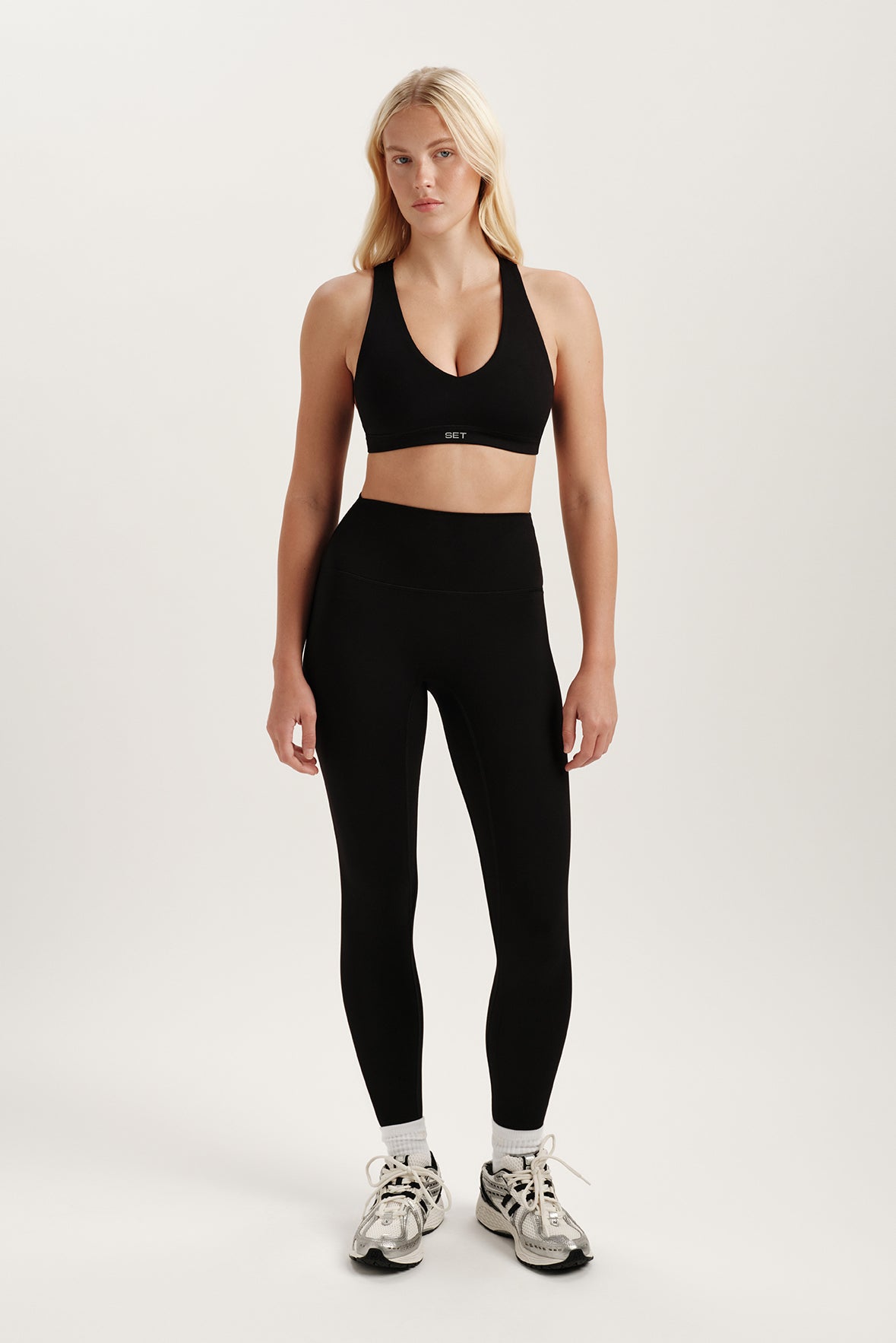 Woman wearing a black sports bra and leggings on a white background