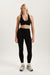 Woman wearing a black sports bra and leggings on a white background