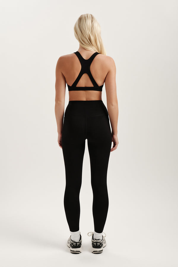 Person wearing a black sports bra and leggings set on a white background