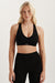 Woman wearing a black sports bra and leggings on a light background <model-info>Kenzie wears a size S and is 5’6, 25” waist, 33” bust.</model-info>