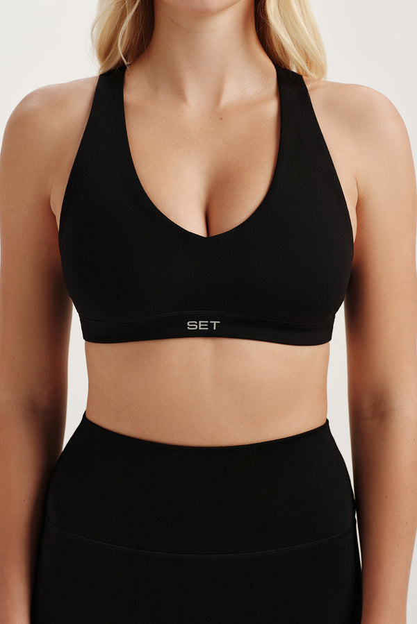 Person wearing a black sports bra with 'SET' branding on a neutral background