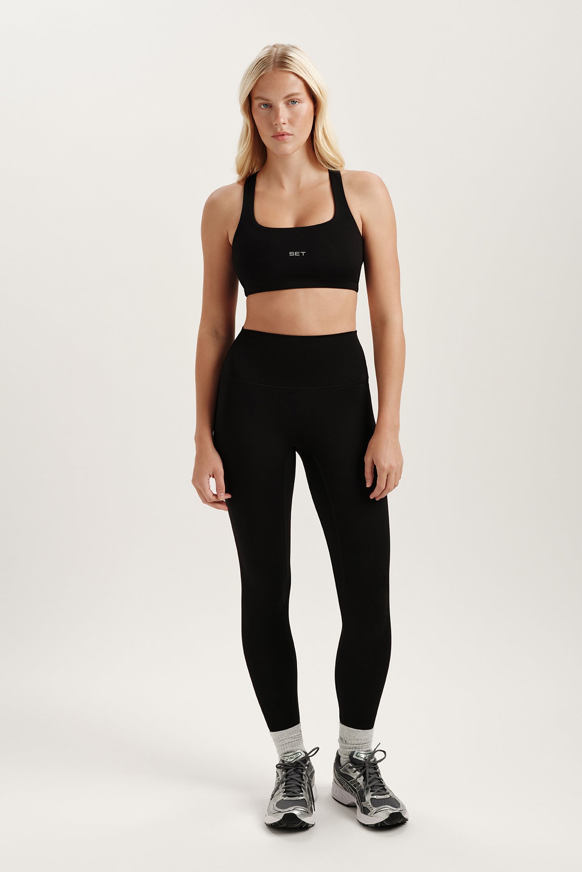 Woman wearing a black sports bra and leggings on a white background