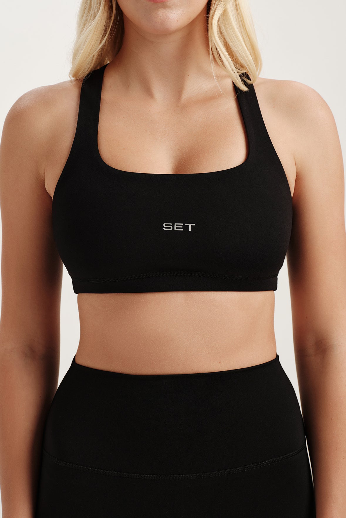 Black sports bra with 'SET' logo worn by a person on a light background