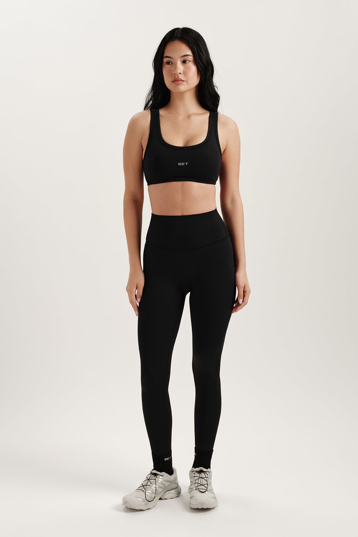 Woman wearing a black sports bra and leggings on a white background