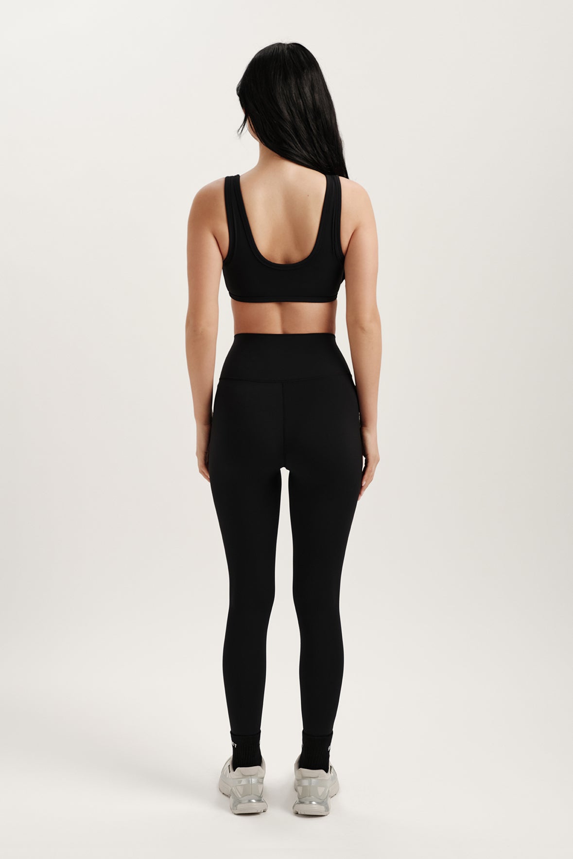 Person wearing a black sports bra and leggings set on a white background