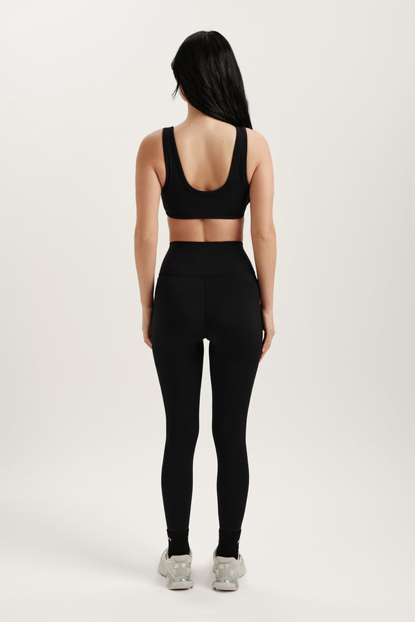 Person wearing a black sports bra and leggings set on a white background