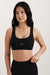 Woman wearing a black sports bra with 'SET' logo on a light gray background <model-info>Jasmine wears a size S and is 5’8, 25” waist, 32C bust.</model-info> 