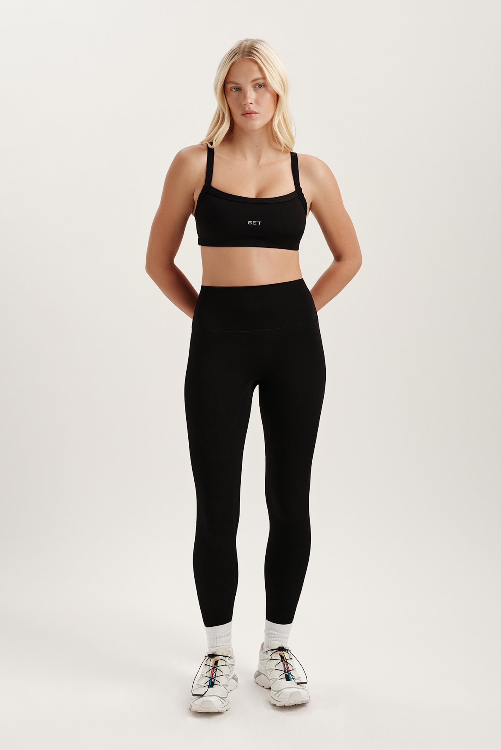 Woman wearing a black sports bra and leggings on a white background