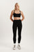 Woman wearing a black sports bra and leggings on a white background
