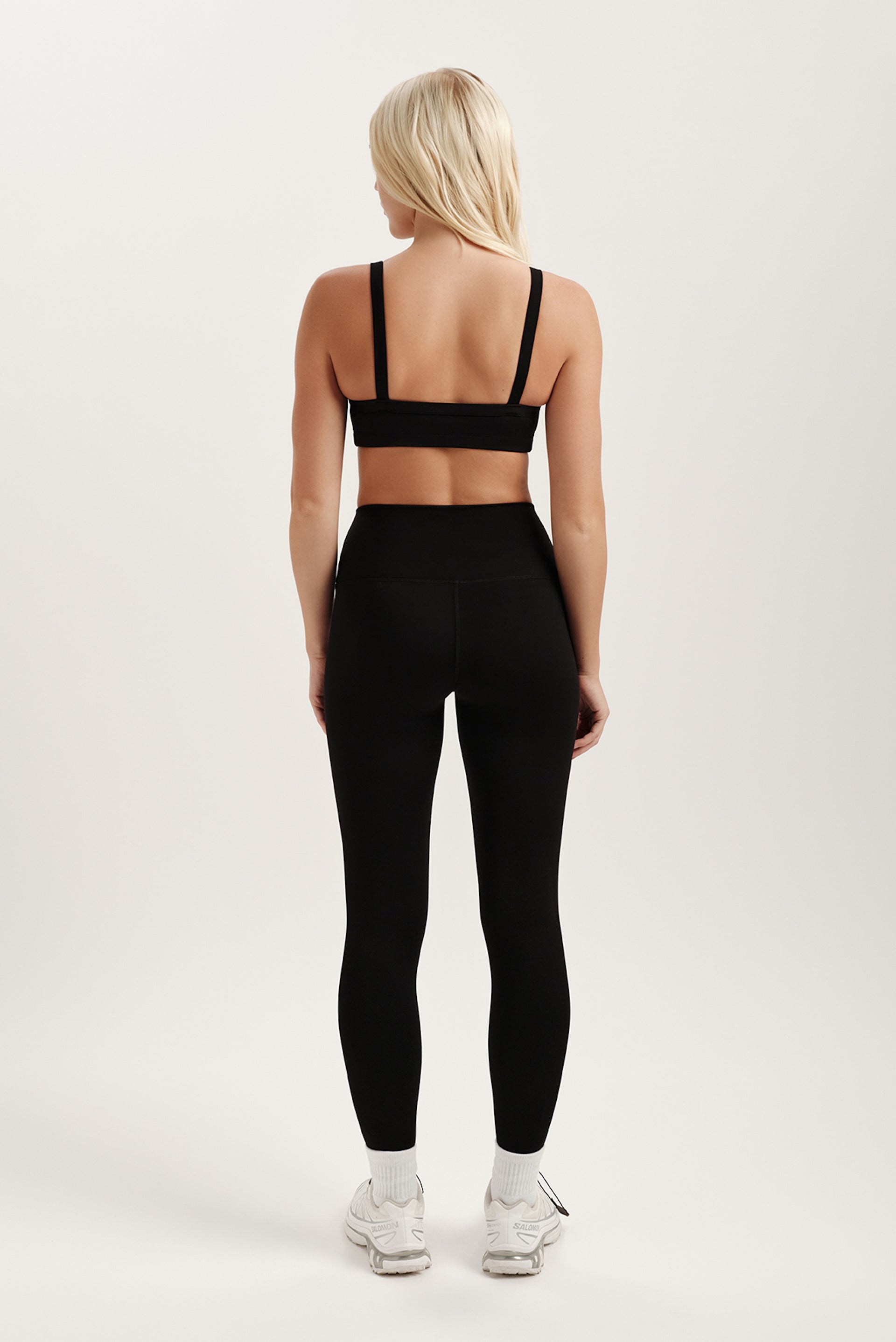 Person wearing a black sports bra and leggings set on a white background