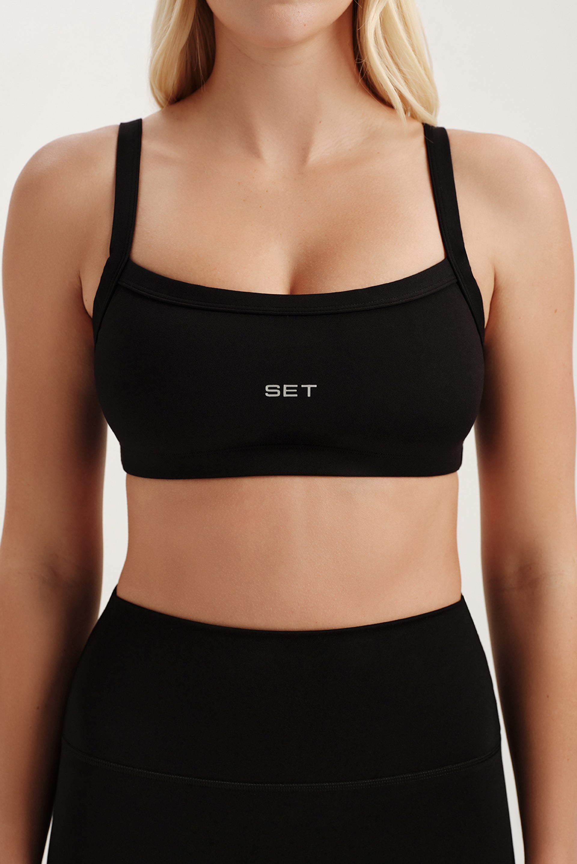 Black sports bra with 'SET' logo worn by a person on a light background