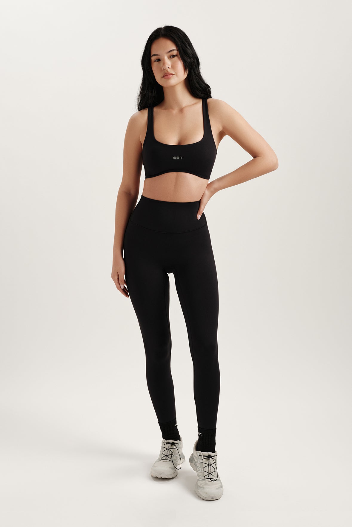 Woman wearing a black sports bra and leggings on a white background