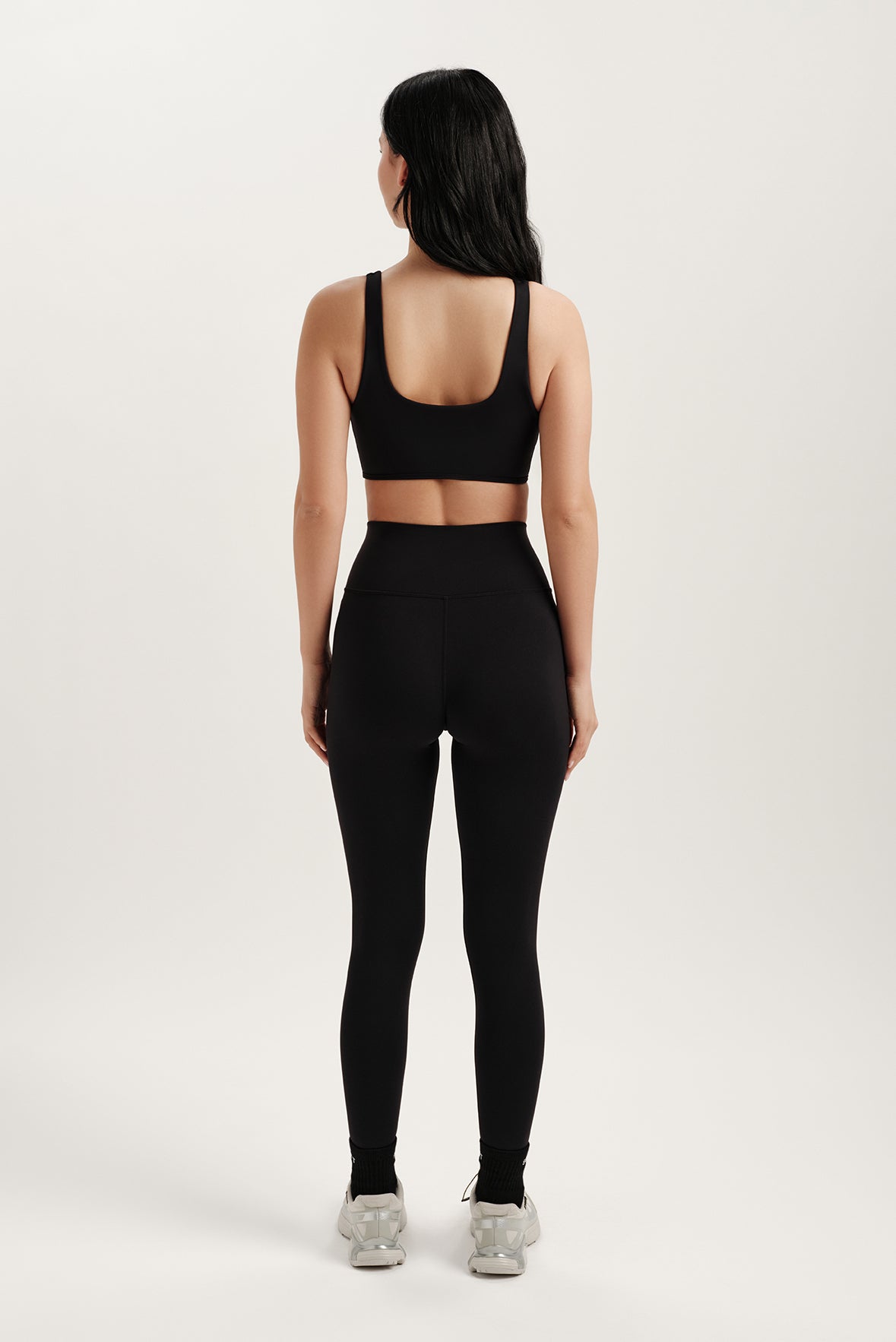 Person wearing a black sports bra and leggings on a white background