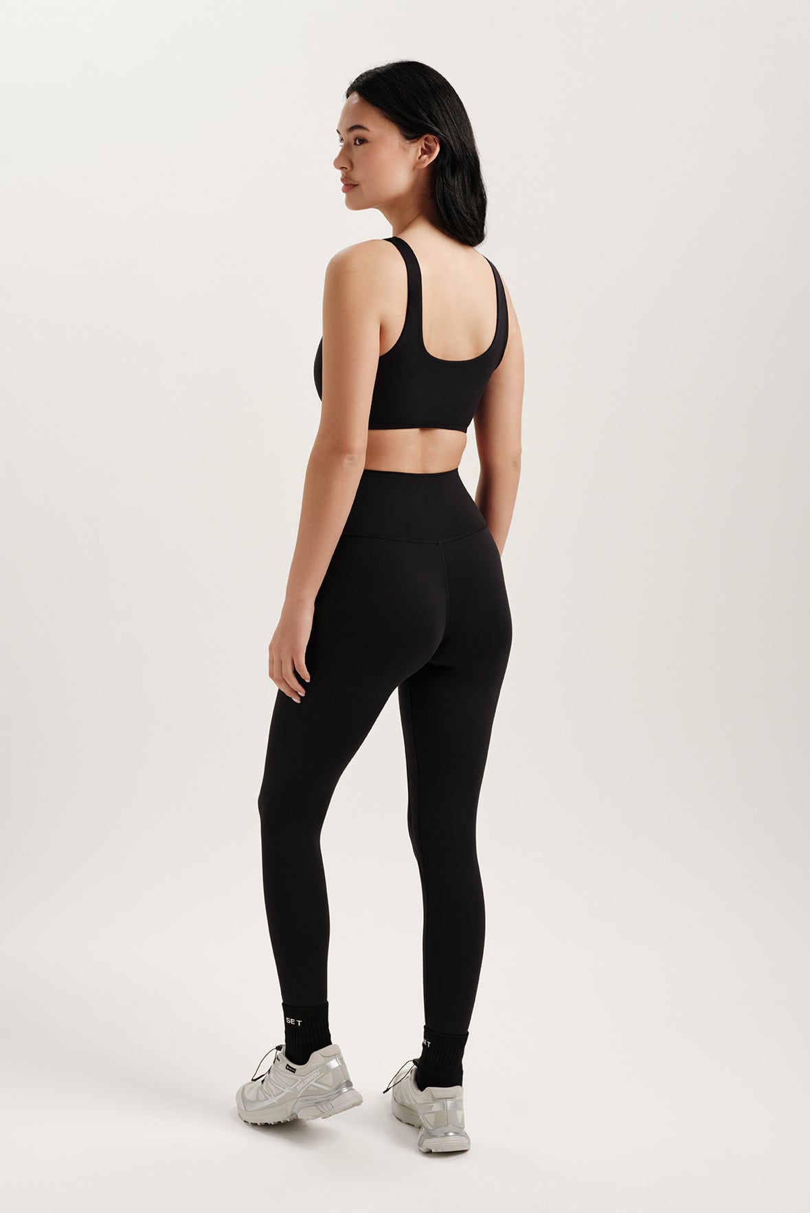 Woman wearing a black sports bra and leggings on a white background