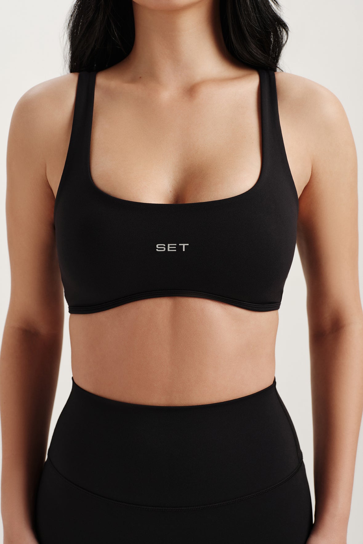 Black sports bra with 'SET' logo worn by a person on a plain background