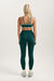 Person wearing a green sports bra and leggings set on a white background