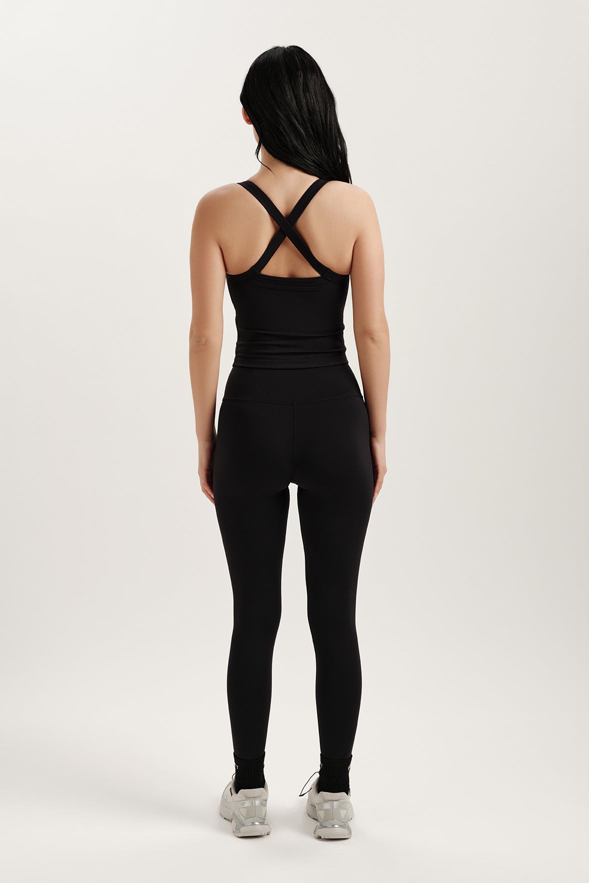 Person wearing a black tank top and leggings set on a white background