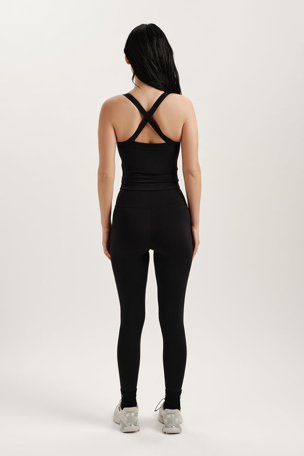 Person wearing a black tank top and leggings set on a white background