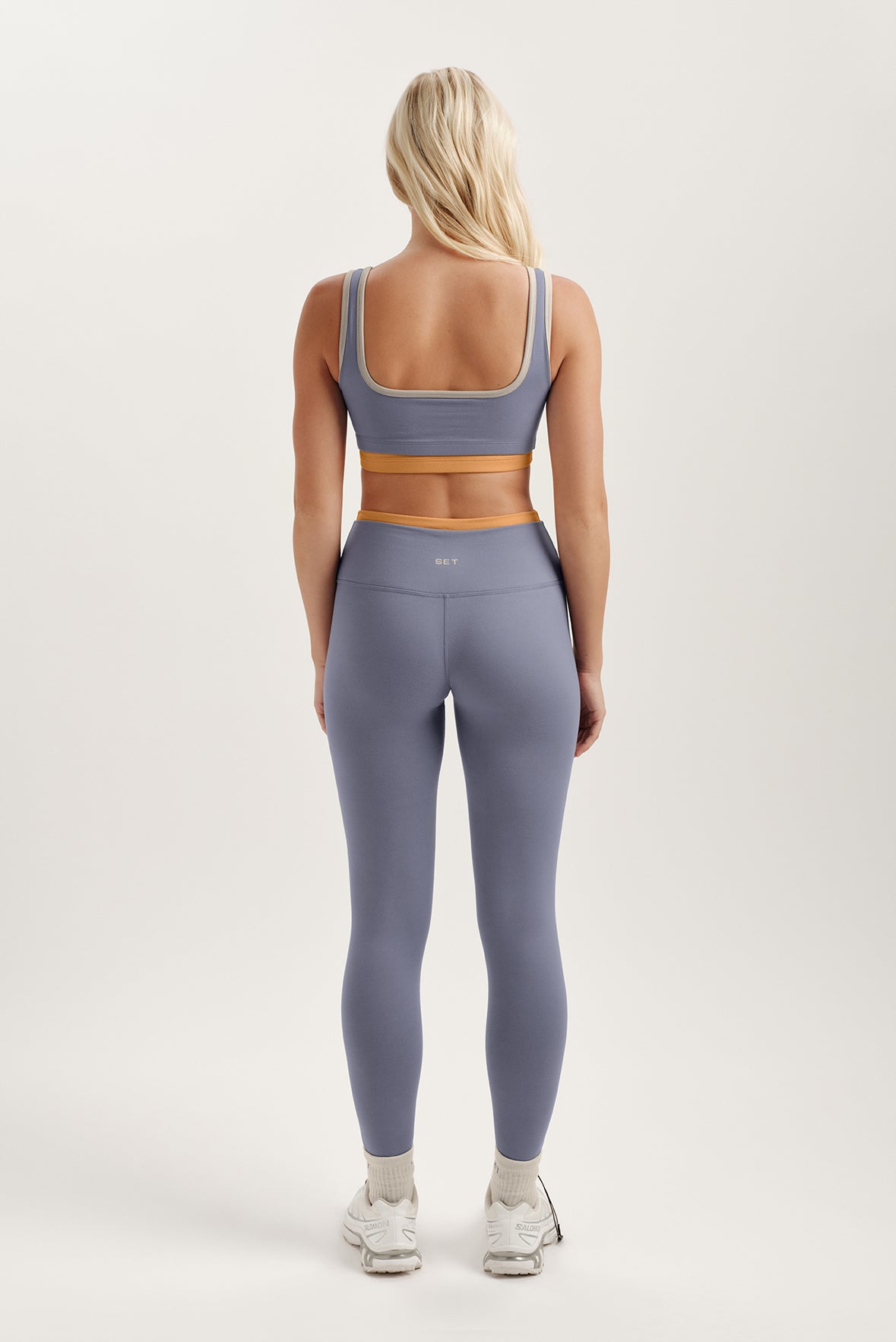 Person wearing a purple sports bra and leggings set on a white background