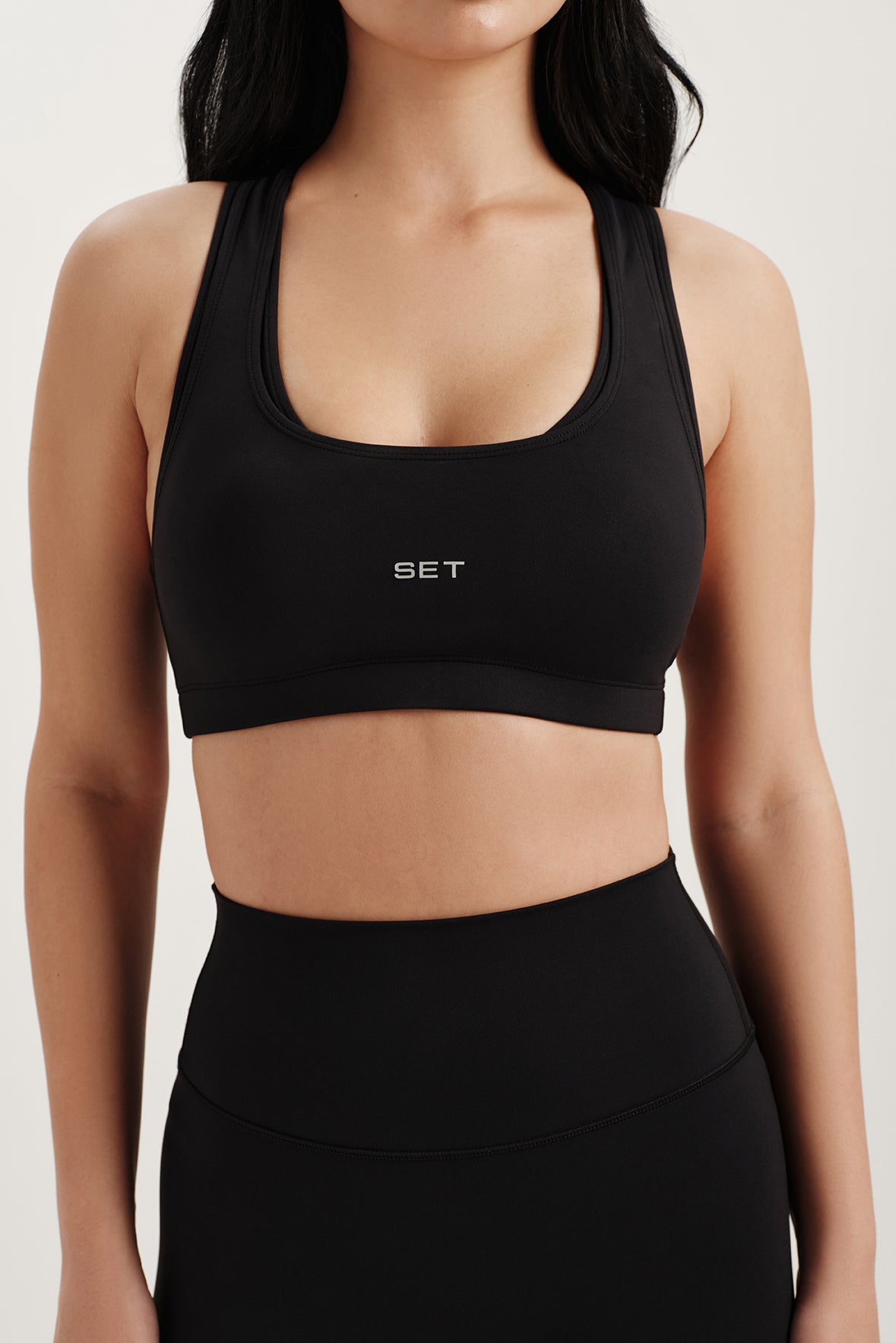Person wearing a black sports bra with 'SET' logo on a white background