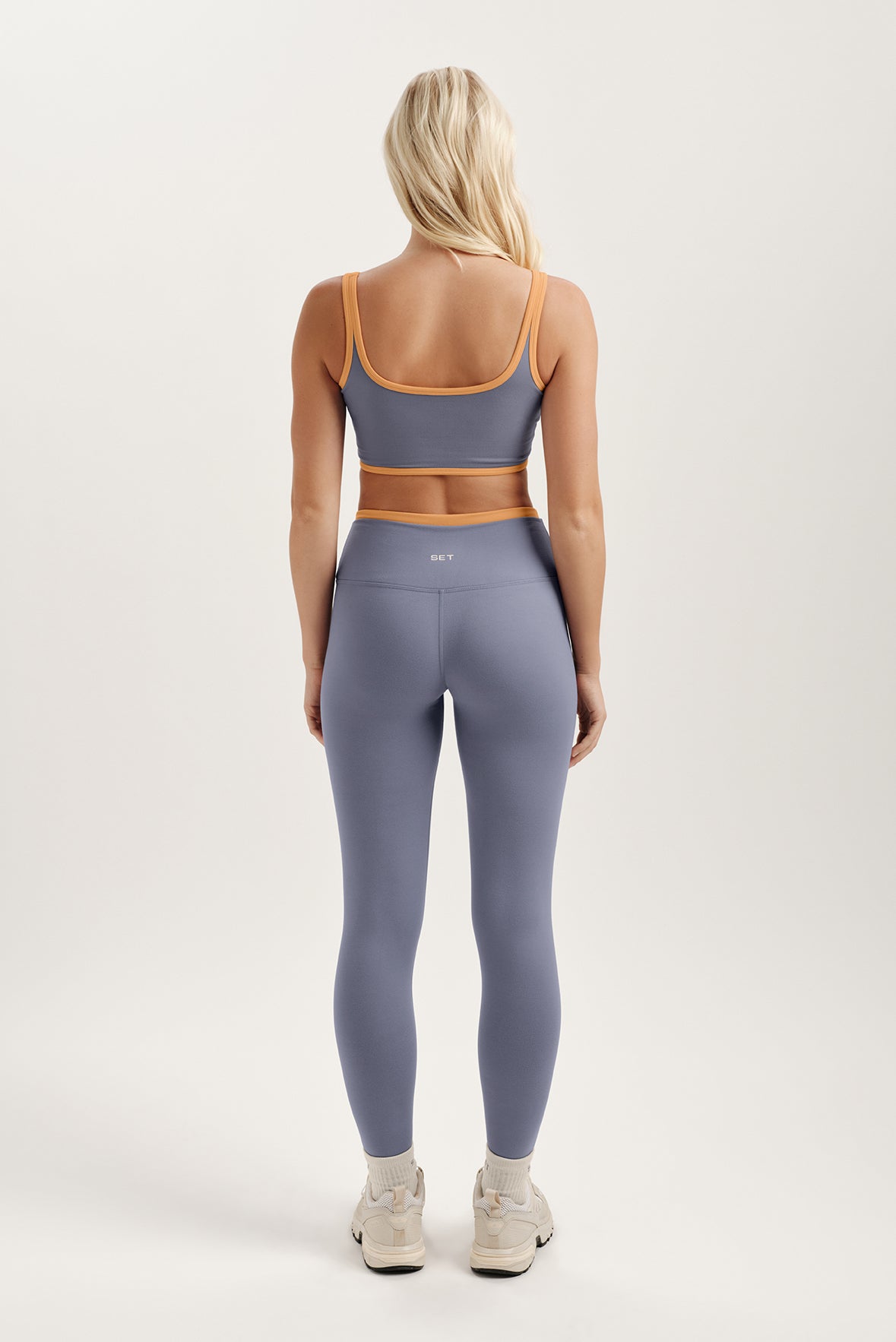 Person wearing a purple sports bra and leggings set on a white background